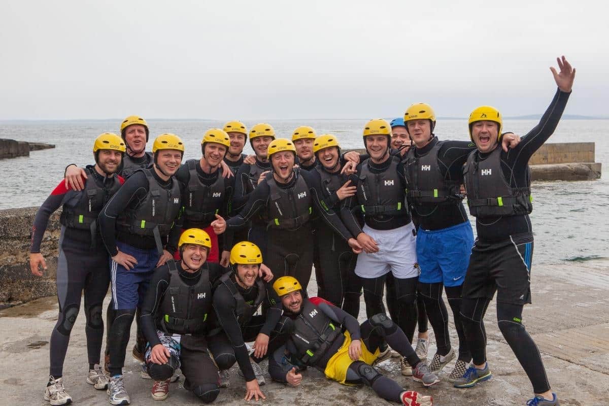Stag party Coasteering with Wild Water Adventures, Kerry Stag group in wetsuits, buoyancy aids and helmets posing by the sea in Fenit, Co. Kerry